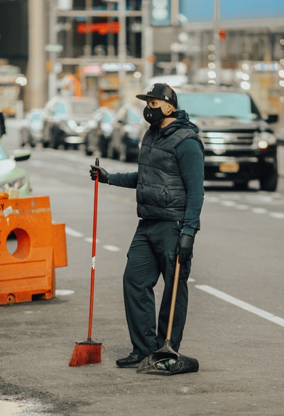 Dressed in a black jacket and black trousers, wearing a black helmets, holding a red stick man standing in the way
